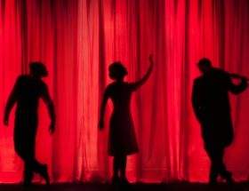 silhouette of three performers on stage