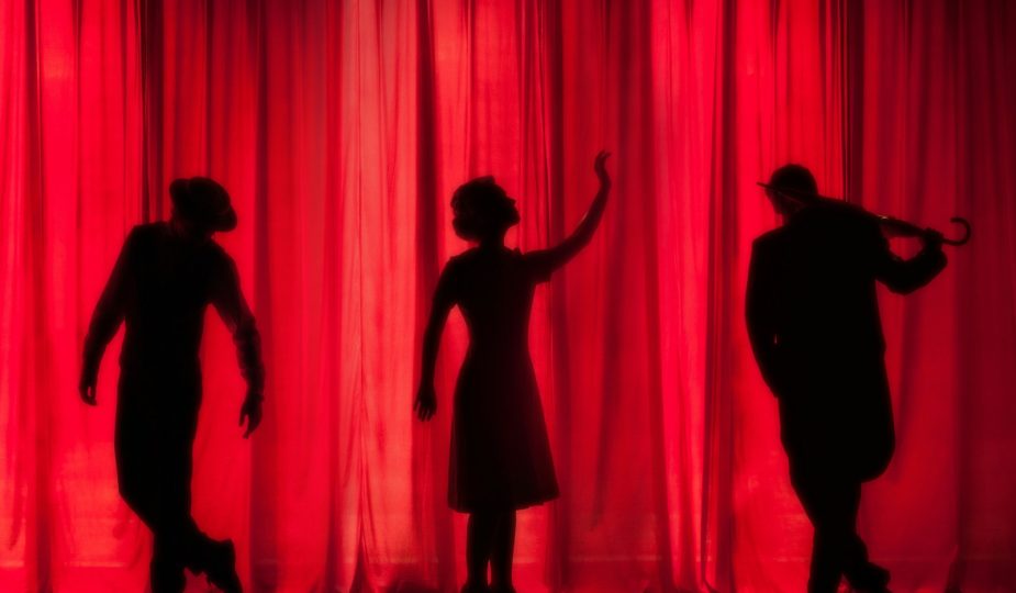 silhouette of three performers on stage